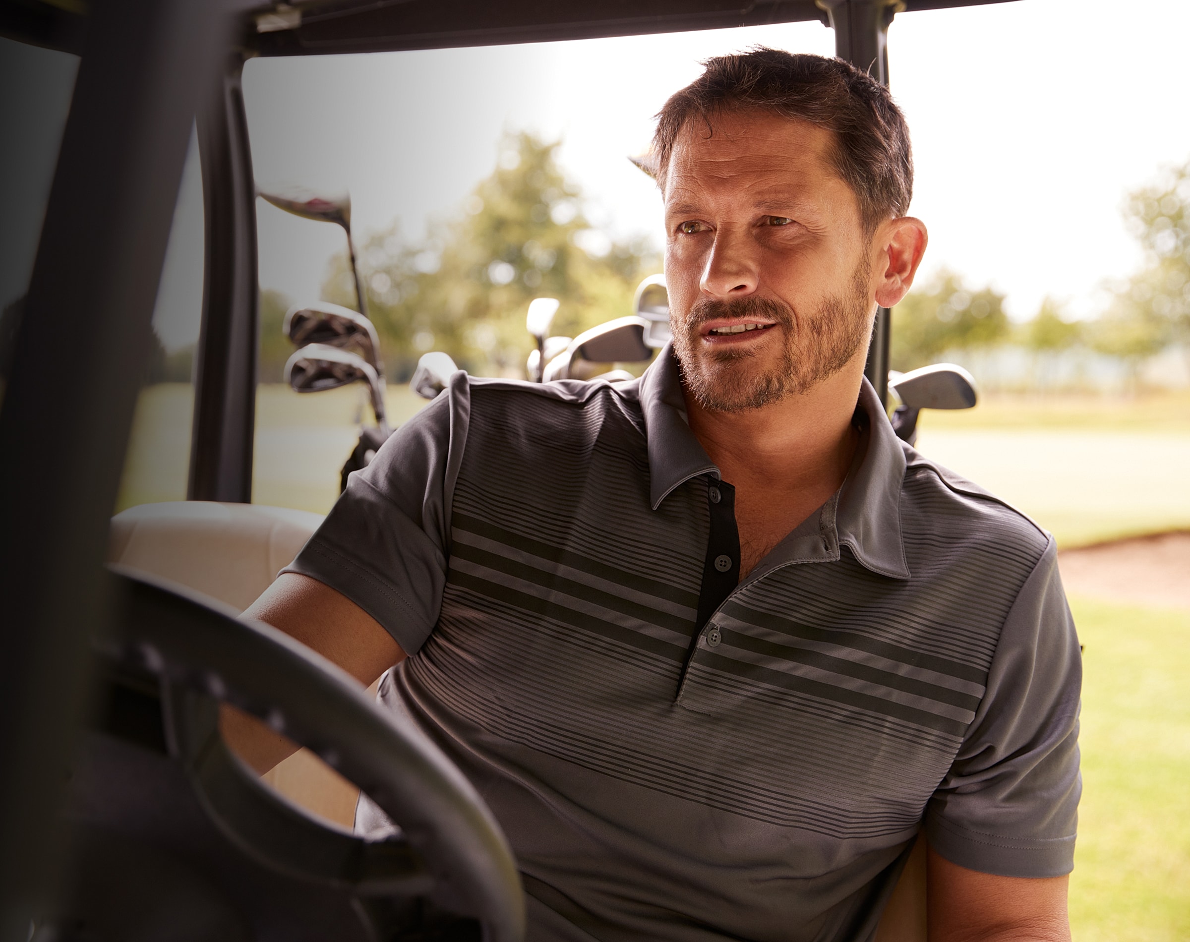 Man sitting in a golf cart on course.